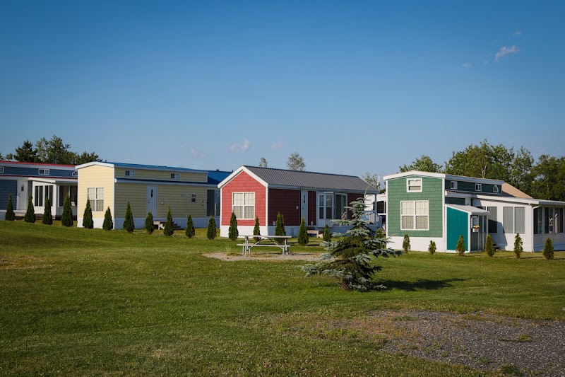 Colorful Narrows Too Campground cabins line a grassy area in Acadia National Park under a clear blue sky.
