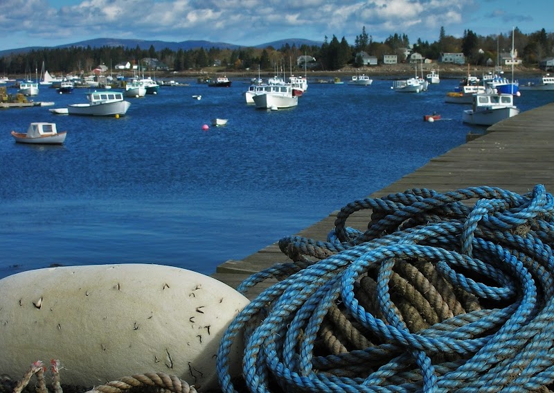 Coastal scene at Bernard Harbor in Acadia National Park, with boats anchored near a weathered pier and coiled mooring ropes.