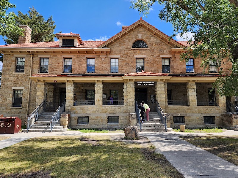 Stone, two-story building with a covered porch in Yellowstone National Park, front steps occupied by visitors.
