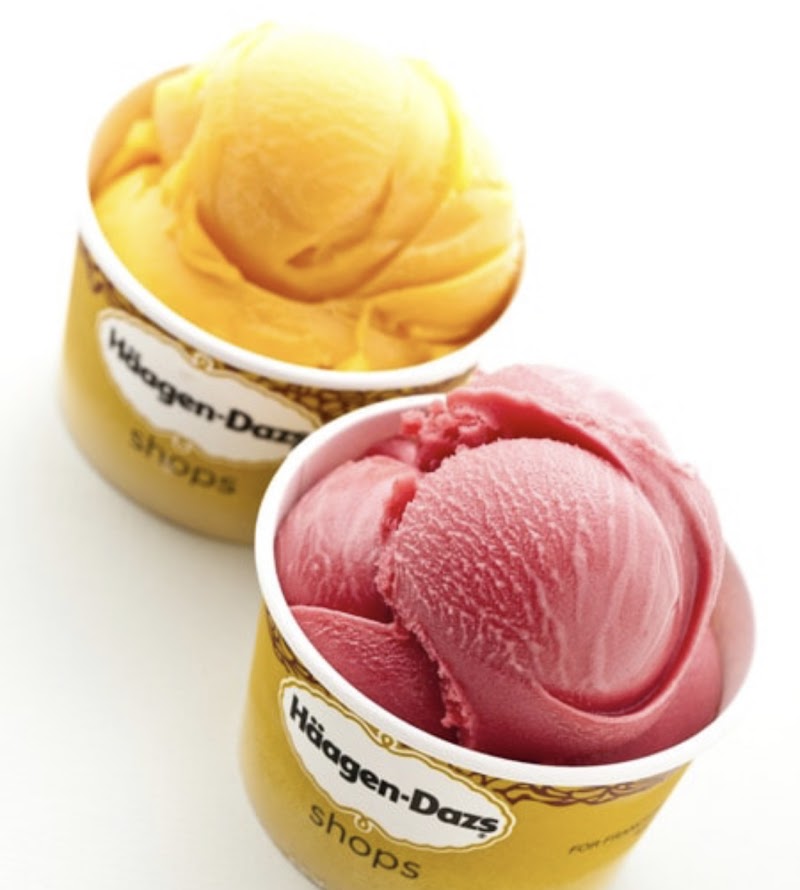 Two scoops of yellow and pink ice cream in yellow cups, resting on a white surface at Yellowstone National Park.