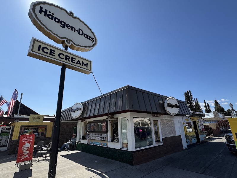 Sunny street scene in Yellowstone National Park with a large vintage ice cream sign and a small storefront offering treats.