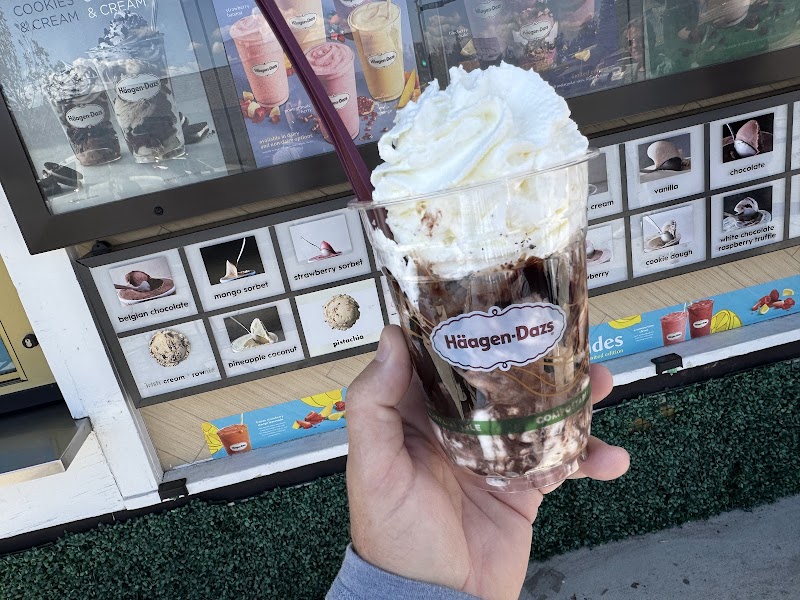 Hand holding a clear cup with whipped cream and chocolate ice cream at a concession stand in Yellowstone National Park.