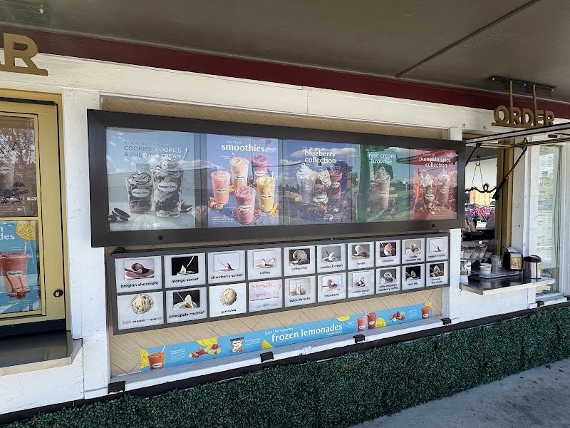 Ice cream shop window at Yellowstone National Park concession, displaying colorful flavor panels and an outdoor order counter.