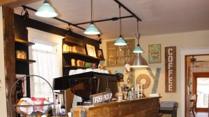 Warm gift shop interior at Badlands National Park with a wooden counter, shelves of souvenirs, and hanging teal lamps.
