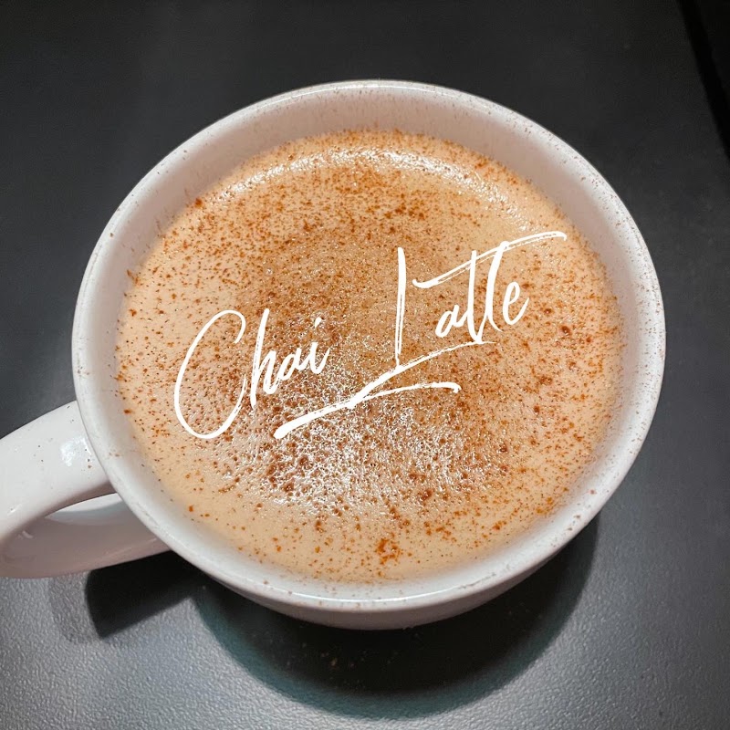 Chai latte with cinnamon dusting in a white mug on a dark table, Badlands National Park gift shop item.