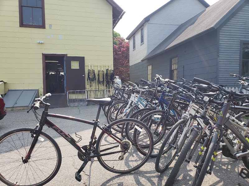 Row of bicycles parked outside a yellow building and a gray house in Acadia National Park, near bike racks.