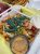 Loaded fries topped with cheese, jalapeños, cherry tomatoes, and blue tortilla chips at a casual burger joint.