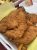 Crispy fried chicken pieces with french fries served in a white takeout tray.