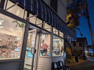 Storefront in Acadia National Park at twilight with a striped awning and glass entrance.