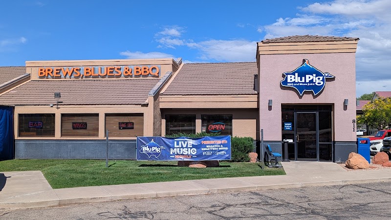 Arches National Park area restaurant building with tan facade, large orange sign, exterior banners, and a bright blue sky.