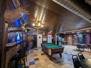 Rustic bar inside Badlands National Park with mounted deer heads, a green pool table, neon signs, and wood paneling.