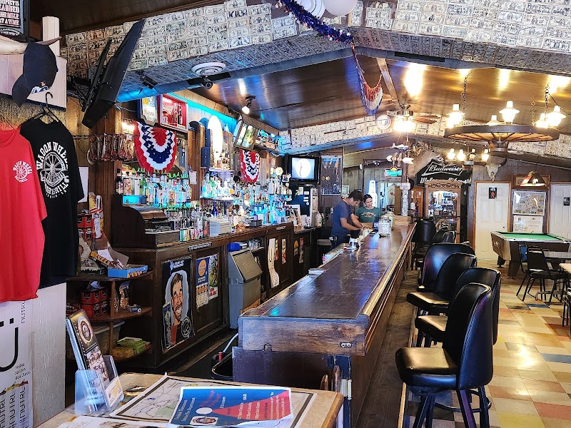 Long wooden bar interior with stools, memorabilia, beer taps, and menu boards inside a tavern at Badlands National Park.