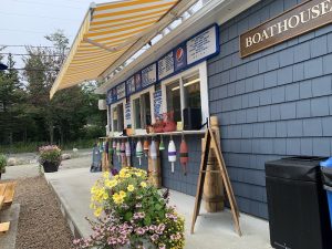 Boathouse storefront near Acadia National Park coast with striped awning and colorful lobster buoys.