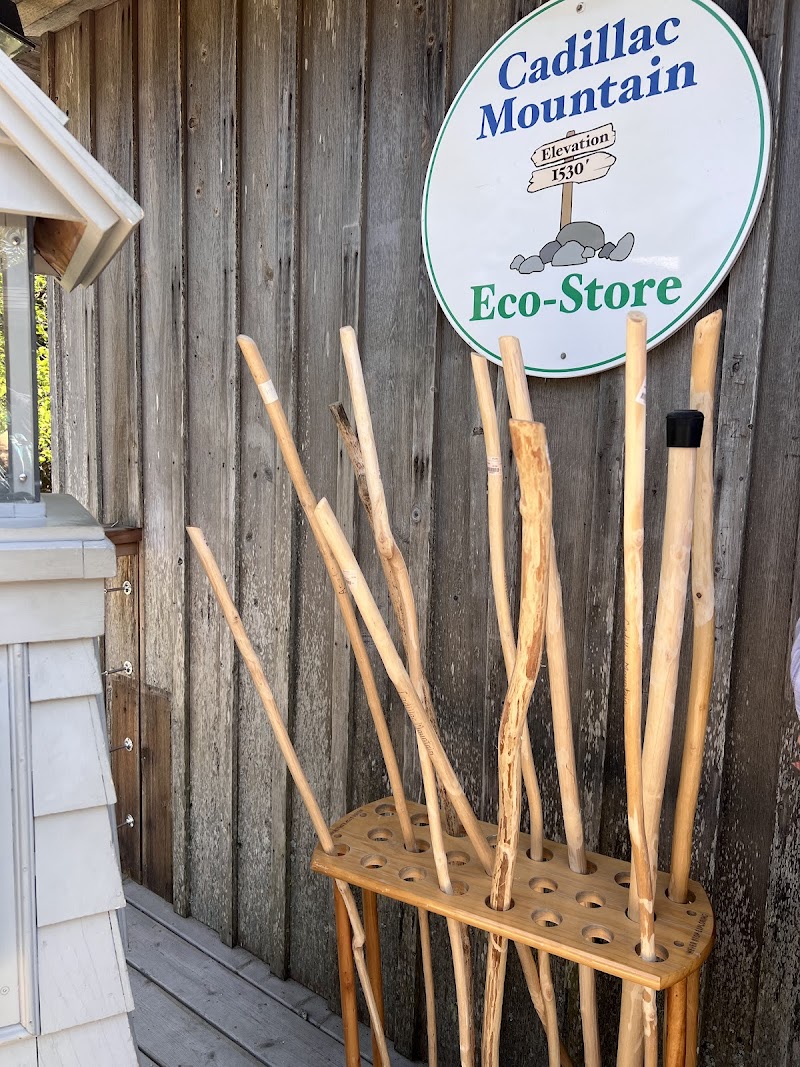 Rustic gift shop exterior in Acadia National Park with a wooden wall, a rack of walking sticks, and a round sign.