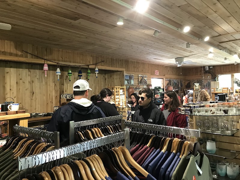 Inside a wooden gift shop in Acadia National Park, visitors browse clothing racks and shelves of souvenirs.