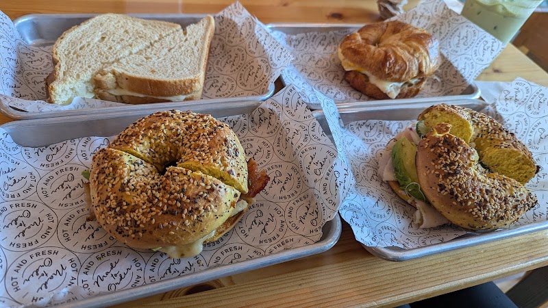 Sesame seed bagels on metal trays with a lettuce-tomato bagel sandwich and a croissant sandwich at Acadia National Park.