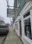 Pastel storefronts line a coastal street in Acadia National Park, with a weathered wooden bakery sign and a parked pickup.