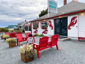 Lobster pound exterior with bright red chairs along a gravel lot near Acadia National Park.