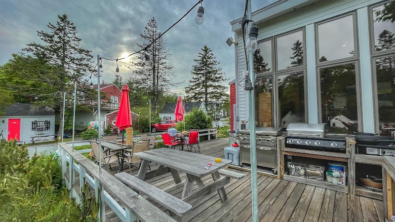 Open Hearth Inn deck at Acadia National Park with picnic tables, string lights, and a grilling area.