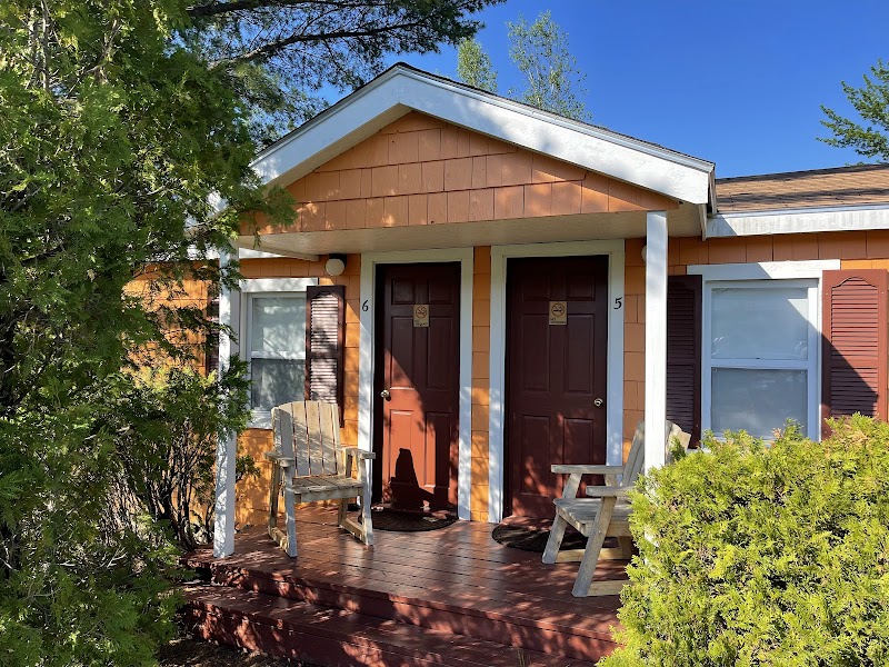 Two-door lodging unit on a sunlit porch in Acadia National Park, with orange siding and Adirondack chairs.