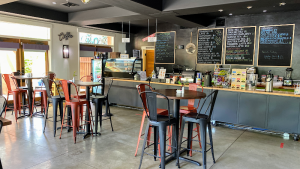 Cafe counter with chalkboard menus, glass display case, and red and black metal tables inside Arches National Park.