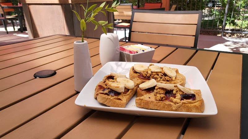 Outdoor cafe table at Arches National Park with banana-topped toast and nuts on a white plate.