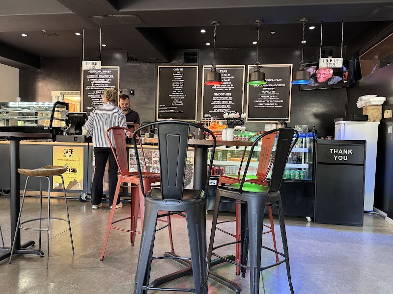 Cozy cafe interior at Arches National Park with a black counter, chalkboard menus, and colorful metal bar stools.