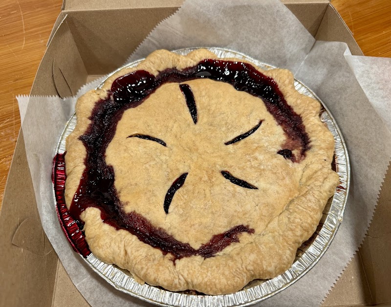 Blueberry pie with a golden flaky crust in a foil pan inside a cardboard takeout box, Acadia National Park.