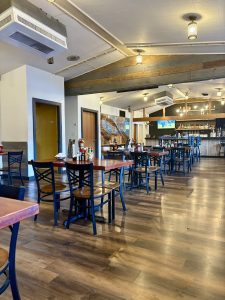 Cozy dining room with tables and blue chairs, warm pendant lights above a bar inside Arches National Park.