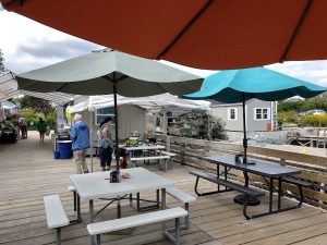 Dining area on the Acadia National Park wharf with large umbrellas and picnic tables overlooking the water.