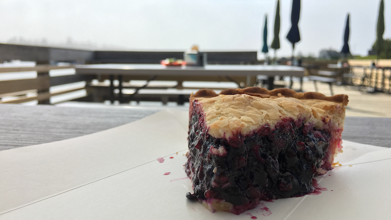 Blueberry pie slice on a table at Lunch on the Wharf, Acadia National Park, with harborfront seating in view.
