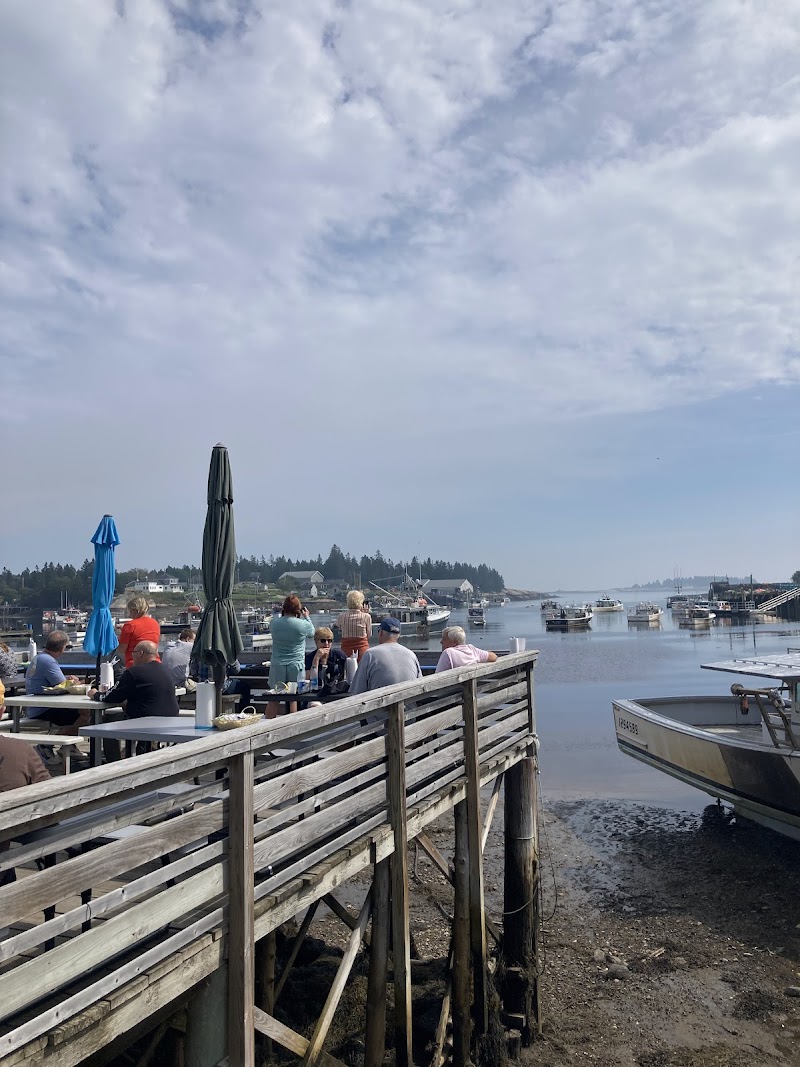 Bar Harbor waterfront dining on the Acadia National Park wharf, with boats docked and diners at wooden tables.