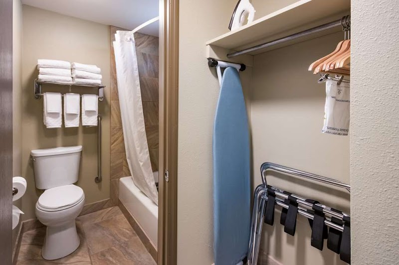 Hotel bathroom in Yellowstone National Park with toilet, towel rack, shower curtain, bathtub and iron/closet area.