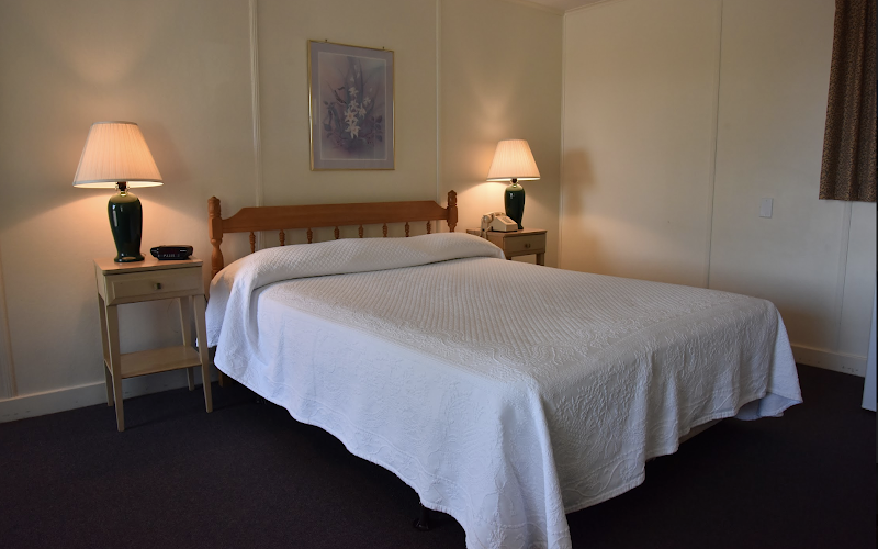 Interior motel room in Acadia National Park with a large bed, two nightstands, and warm lamps.