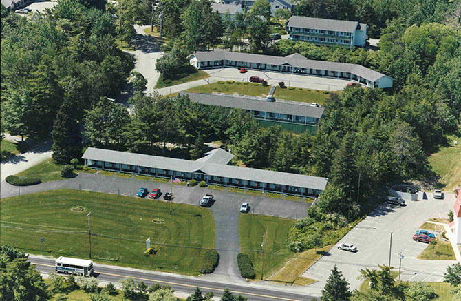 Edenbrook Motel complex in Acadia National Park nestled among pines with manicured lawns and a parking lot.