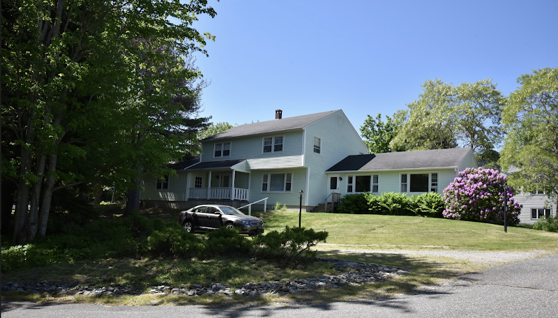Lodging building sits amid green lawns and trees in Acadia National Park, offering a quiet coastal lodging setting.