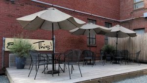 Outdoor restaurant patio with multiple umbrellas and metal chairs in Acadia National Park.