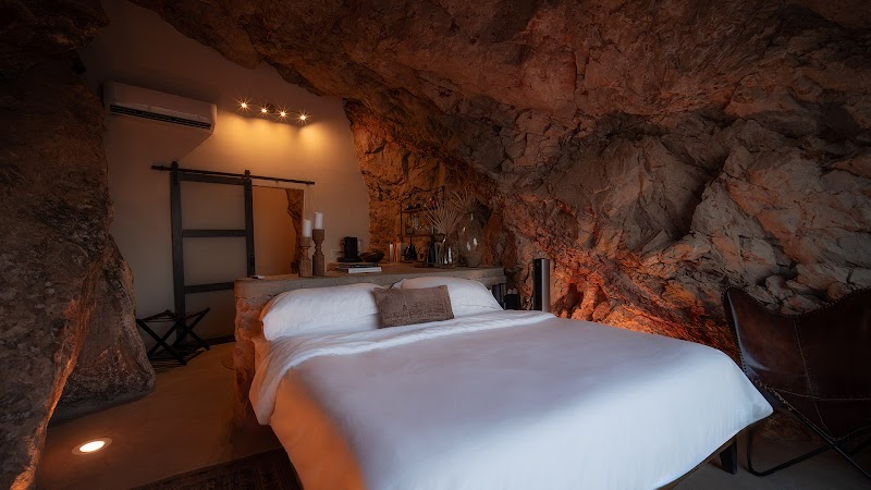 Rock-walled bedroom inside a Big Bend National Park lodging with white linens and warm ambient lighting.