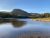 Sand Beach at Acadia National Park lies along a rocky shore with autumn foliage and Cadillac Mountain in the distance.