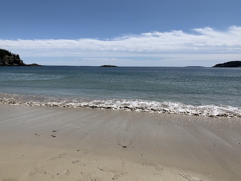 Sand Beach at Acadia National Park with turquoise water, pale sand, and rocky headlands under a clear blue sky.