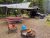 Glacier National Park campground with a black SUV under a tarp shade, string lights, picnic table, chairs, and a fire pit.