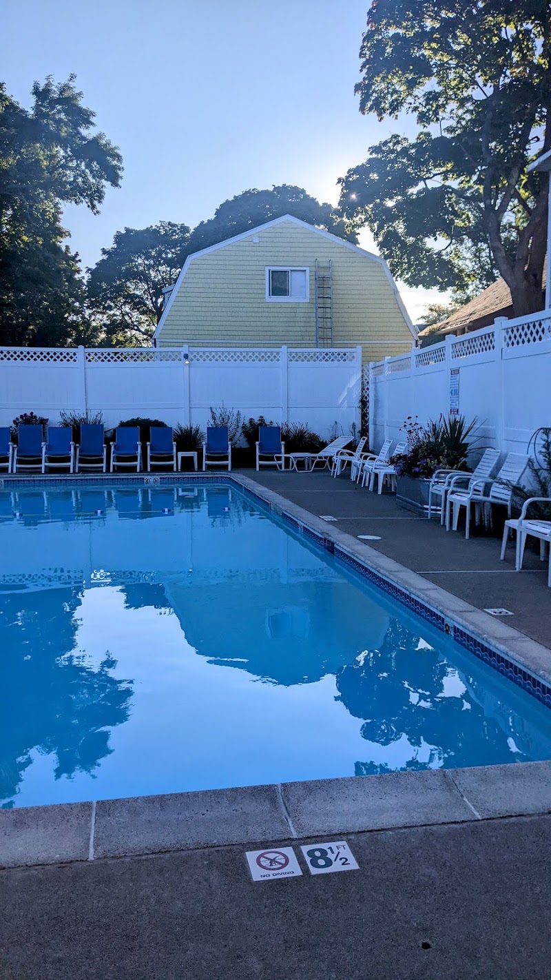 Sunny pool area at Acadia National Park lodging, blue water, white fencing, and rows of lounge chairs.