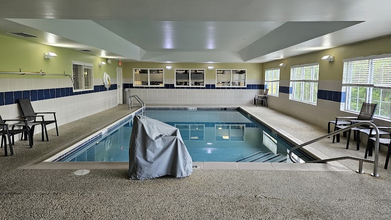 Indoor hotel pool near Ellsworth in Acadia National Park, with white tiles, blue accents, and large windows.