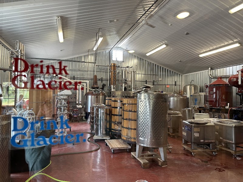 Inside a distillery facility near Glacier National Park, with stainless steel tanks, copper fittings and wooden aging casks visible.