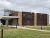 Modern visitor center with rust-colored metal panels, stone accents, glass entry, and a paved path at Badlands National Park.