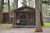 Glacier National Park rustic campground cabin with a shaded porch,set among tall pines and a gravel path.