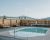 Outdoor pool on a wooden deck with a metal handrail, benches along a privacy fence, overlooking a lake and distant hills in Yellowstone National Park.