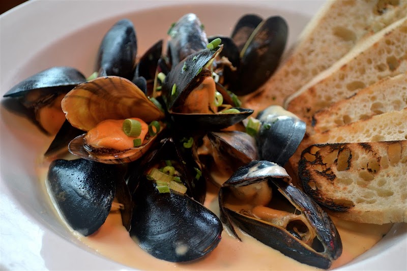 Mussels in a creamy orange sauce with crusty bread, garnished with chives, in Acadia National Park.
