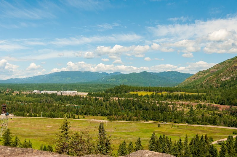 Columbia Mountain Trailhead overlooks a broad valley with forests and distant mountains in Glacier National Park.