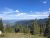 Columbia Mountain Trailhead overlook in Glacier National Park reveals forested slopes and snow-capped peaks.